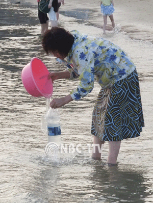 폭염 속 바닷가에서 물 퍼는 여인